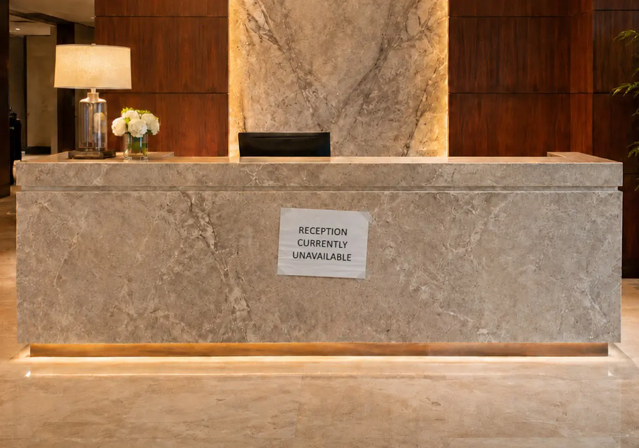 Unstaffed reception desk with temporary sign: Reception currently unavailable